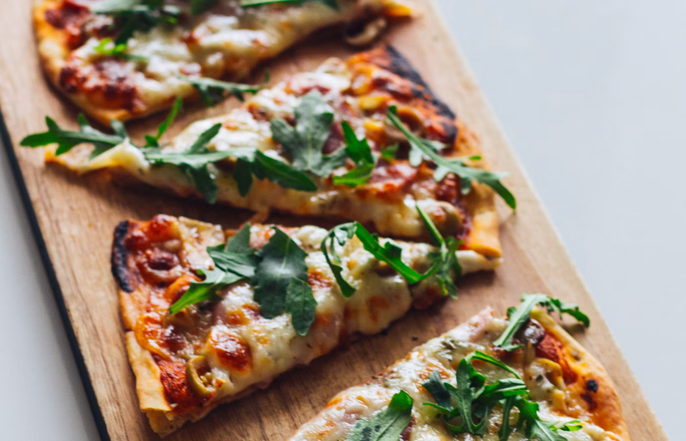 Pizza with prosciutto and green leaves
